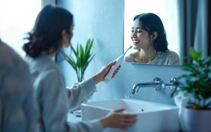 une-personne-se-brosse-les-dents-avec-une-brosse-a-dents-electrique-devant-un-miroir-dans-une-salle-de-bains-moderne-mousse-visible-sur-la-brosse-gouttes-deau-sur-le-plan-de-travail-petite-pl