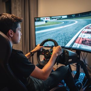 Un jeune pilote débutant conduit un simulateur de course dans un cockpit réaliste, avec un circuit virtuel et une trajectoire idéale lumineuse visible sur la piste.